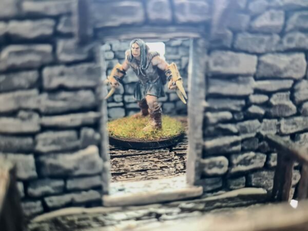 Figurine d'orc guerrier franchissant une porte de donjon en pierre, décor miniature impression 3D avec brossage à sec, ambiance médiévale fantastique pour JDR, Les Trésors du Donjon.