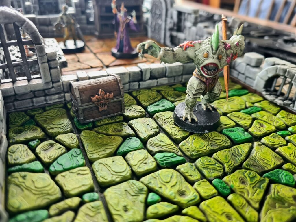 Figurine de monstre de la boîte HeroQuest sur des dalles de sol vertes texturées style poison ou mousse.