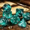 dés JDR turquoise set de 7 dés polyédriques turquoise avec paillettes, D20 et D12 empilés près d'un grimoire